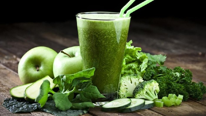 Glass of fresh green vegetable juice with two drinking straws on rustic wood table. The glass is surrounded by green vegetables like spinach, lettuce, broccoli, celery, green apples, parsley and cucumber. This is a drink used for detox diet. Predominant colors are green and brown.  DSRL studio photo taken with Canon EOS 5D Mk II and Canon EF 70-200mm f/2.8L IS II USM Telephoto Zoom Lens