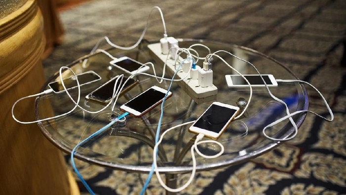 Group of smartphones charging on the glass table with sharing the same AC plug
