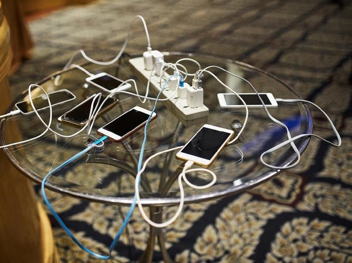 Group of smartphones charging on the glass table with sharing the same AC plug