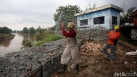 Para pekerja melakukan pengerjaan batu bronjong untuk perbaikan sementara tanggul sungai Bekasi yang sebelumnya jebol hingga menyebabkan rumah warga terendam banjir.