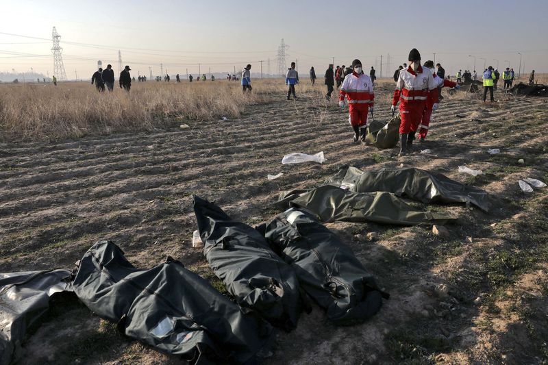 Rescue workers carry the body of a victim of an Ukrainian plane crash in Shahedshahr, southwest of the capital Tehran, Iran, Wednesday, Jan. 8, 2020. A Ukrainian airplane carrying 176 people crashed on Wednesday shortly after takeoff from Tehran's main airport, killing all onboard. (AP Photo/Ebrahim Noroozi)