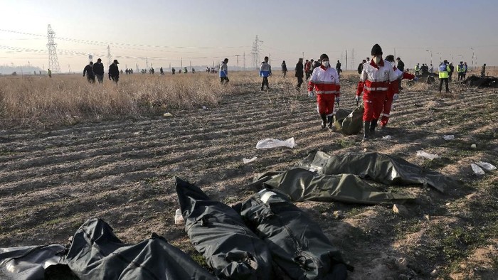 Rescue workers carry the body of a victim of an Ukrainian plane crash in Shahedshahr, southwest of the capital Tehran, Iran, Wednesday, Jan. 8, 2020. A Ukrainian airplane carrying 176 people crashed on Wednesday shortly after takeoff from Tehrans main airport, killing all onboard. (AP Photo/Ebrahim Noroozi)