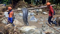 Petugas menggotong kabel melewati Sungai Ciberang untuk memperbaiki jaringan listrik yang rusak terkena banjir bandang di Kampung Jaha, Banjar Irigasi, Lebak, Banten, Kamis (9/1/2020).