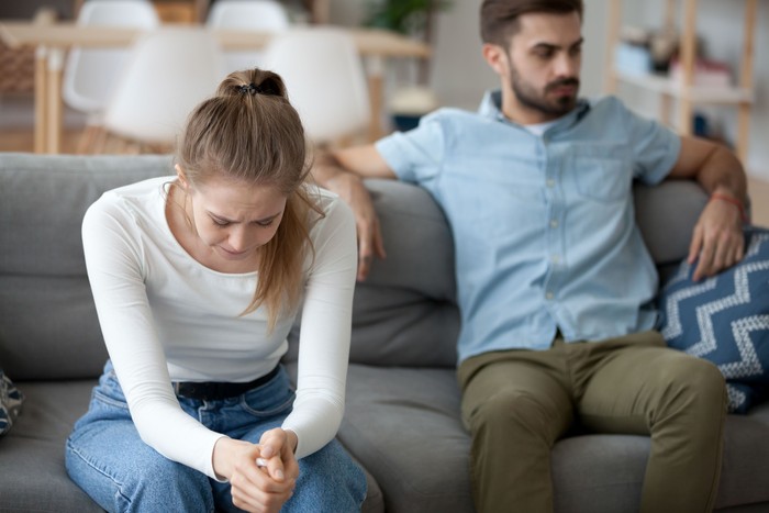 pelakor Unhappy young millennial married couple sitting on couch in living room after quarrel fight. Angry husband frustrated offended wife at home. Break up, divorce and misunderstanding in relations concept