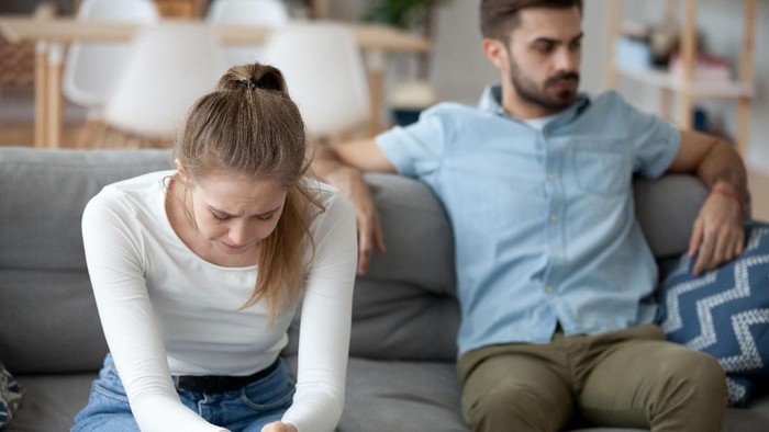pelakor Unhappy young millennial married couple sitting on couch in living room after quarrel fight. Angry husband frustrated offended wife at home. Break up, divorce and misunderstanding in relations concept