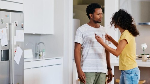 Couple lying in bed while someone is watching in front of the door