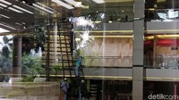 Di dalam gedung, tampak para pekerja sibuk memperbaiki tiang-tiang hiasan yang rusak akibat banjir.