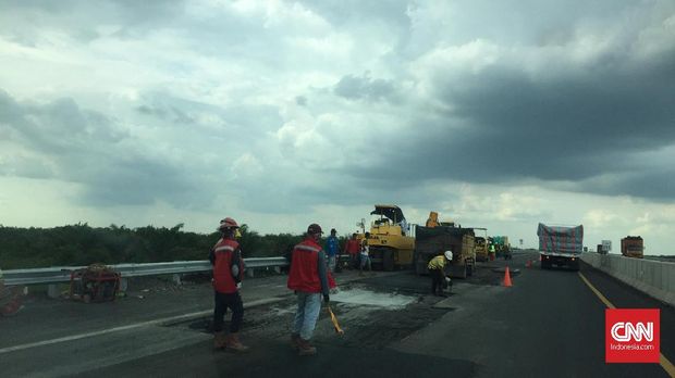 Sejumlah pekerja sedang memperbaiki jalan tol yang rusak.