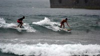 Mereka asyik bermain surfing meski hujan deras mengguyur Pantai Pangandaran.
