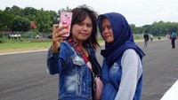 Dua orang warga asyik swafoto di landasan pacu bandar udara Ngloram.