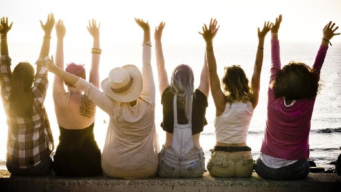 rear view of group of females caucasian friends enjoying at the sunset with ocean in background - success and satisfaction concept for nice people together with joy - friendship and vacation
