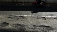Terlihat sejumlah pengendara memperlambat dan berhati hati-hati saat melintas di titik jalan berlubang.