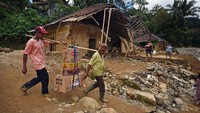 Warga menggotong barang-barang belanjaan melewati rumah yang rusak akibat diterjang banjir bandang di Kampung Muhara, Lebak Gedong, Lebak, Banten, Minggu (12/1/2020). Antara Foto/Asep Fathulrahman.