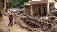 Warga melintasi jalan berlumpur di Kampung Calung Bungur, Sajira, Lebak, Banten, Minggu (12/1/2020). Hampir dua pekan setelah bencana warga di daerah itu belum mendapat bantuan alat berat untuk membersihkan lumpur dan puing yang terbawa banjir. Antara Foto/Weli Ayu Rejeki.