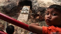Perbaikan jalan amblas itu menjadi tontonan anak-anak.