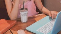 Pose santai itu juga ditunjukkan kala Dara Arafah ngopi di kafe seperti pada foto ini. Seakan sibuk memainkan laptop, Dara tetap menebarkan senyuman sambil ditemani dengan segelas minuman segar. Foto: Instagram @daraarafah
