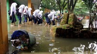 Siswa SMP Negeri 21 Makassar, Sulawesi Selatan, pulang lebih awal akibat banjir merendam bangunan sekolah tersebut, Senin (13/1/2020).