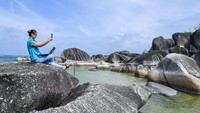 Seorang pengunjung berswafoto di atas bongkahan batu granit di Alif Stone Park, Desa Sepempang, Kabupaten Natuna, Provinsi Kepulauan Riau.