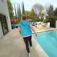 Area kolam renang dilengkapi sofa dan meja serta tenda payung berwarna-warni khas Jojo Siwa, yakni biru muda dan pink. Foto: Screenshot YouTube/ Its Jojo Siwa