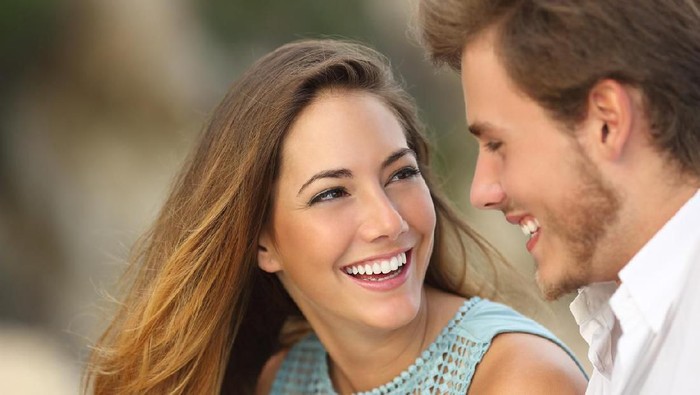 zodiak Front view portrait of a happy couple with perfect smile looking at you sititng on a couch in the living room at home in winter