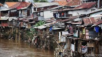 Rumah semi permanen tampak berderet di bantara sungai. Sampah juga terlihat tersangkut di tiang rumah dan batang pohon.