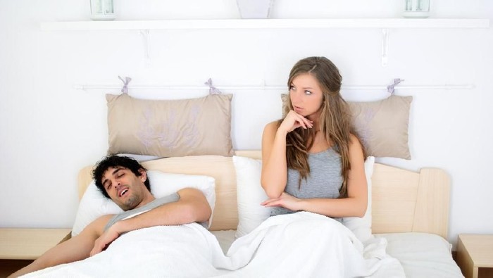 pasangan di tempat tidur Young couple lying in bed, woman in foreground, portrait