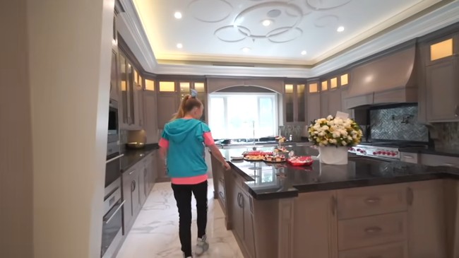 Dapur superluas yang menyatu dengan pintu masuk dan ruang tamu digunakan untuk menjamu para pengunjung yang datang ke rumahnya. Dilengkapi island, mesin pembuat kopi dan kulkas yang semuanya berukuran besar. Foto: Screenshot YouTube/ Its Jojo Siwa