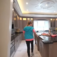 Dapur superluas yang menyatu dengan pintu masuk dan ruang tamu digunakan untuk menjamu para pengunjung yang datang ke rumahnya. Dilengkapi island, mesin pembuat kopi dan kulkas yang semuanya berukuran besar. Foto: Screenshot YouTube/ Its Jojo Siwa