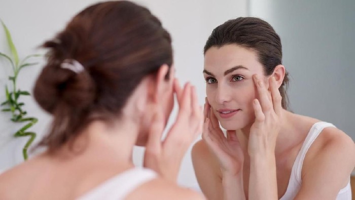 Shot of a beautiful young woman feeling her skin during her beauty routine at home