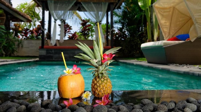 Nicely decorated coconut and pineapple cocktails on pool side in luxury villa on Bali island