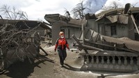 Seorang anggota tim penyelamat menyisir rumah-rumah warga di kawasan Talisay, Provinsi Batangas, Filipina, yang diselimuti abu vulkanik akibat erupsi Taal Volcano, Selasa (14/1) waktu setempat. AP Photo/Basilio Sepe.