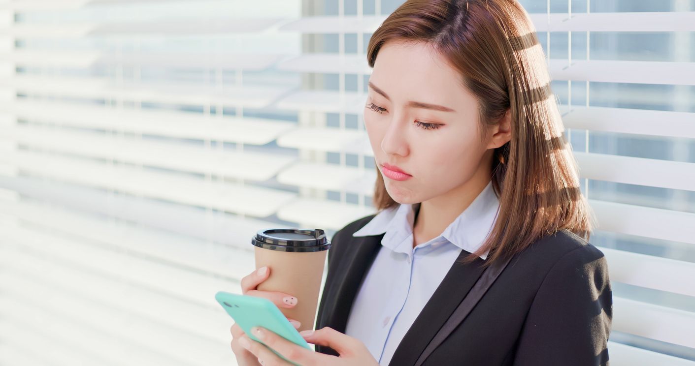 business woman feel depress and use smart phone while drinking coffee in the office