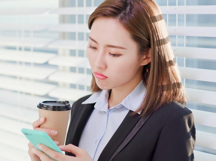 zodiak business woman feel depress and use smart phone while drinking coffee in the office