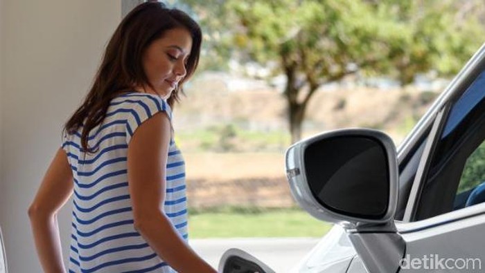 Pengendara wanita mengisi baterai mobil Chrysler Pacifica