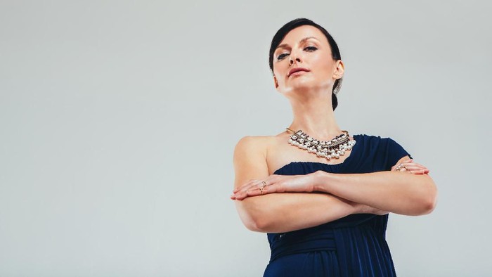 Studio portrait of an attractive woman wearing an elegant evening gown against a gray background