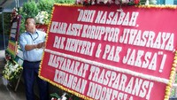 Seorang pria berdiri di depan karangan bunga dukungan di halaman Kementerian BUMN Jakarta, Kamis (16/1/2020).