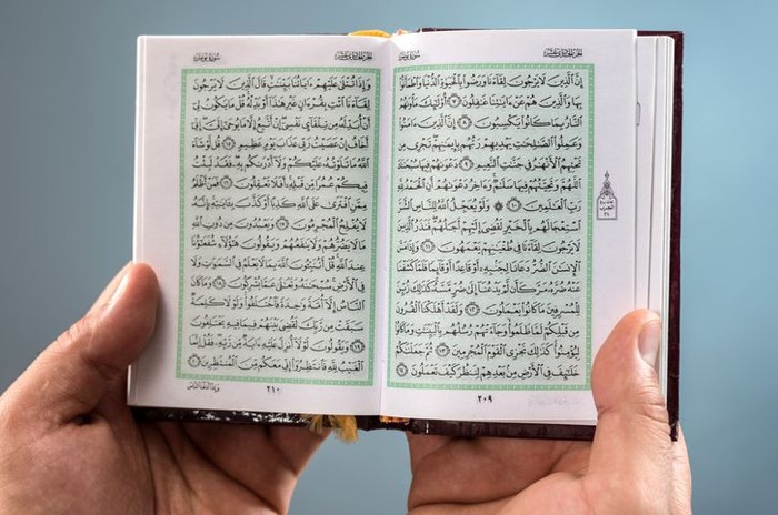 Man hands holding an open Holy Koran.