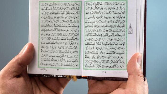 Man hands holding an open Holy Koran.