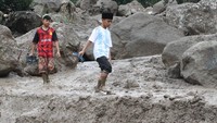 Anak-anak melintas diantara material banjir bandang, di Nagari Malalo, Kab.Tanah Datar, Sumatera Barat, Jumat (17/1/2020). Banjir bandang terjadi pada Jumat pagi tersebut mengakibatkan empat rumah rusak berat, sejumlah kendaraan warga hanyut dan akses jalan menuju ke Padangpanjang via nagari Malalo putus total.