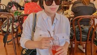Segelas minuman rasa strawberry jadi teman santai Elvia. Mengenakan kemeja putih dan kacamata hitam, Elvia tampak asyik duduk di sebuah kafe di Osaka, Jepang.  Foto: instagram @elviacerolline