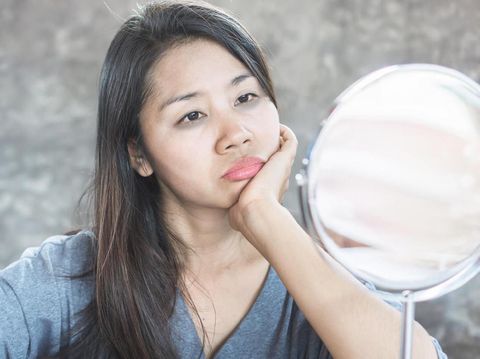 Kulit Kusam unhappy Asian woman age 40 checking her dark eyes circle problem in mirror