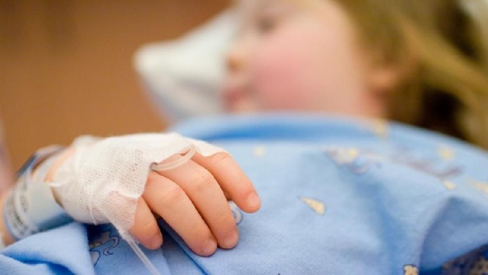 Anak sakit Close up of the hand of a little girl, lying in a hospital bed. Hand is tied down, with tube for an infusion. Focus on the hand.