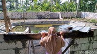 Di kedua sisi kolam terdapat tiga undakan di atas air yang keruh. 