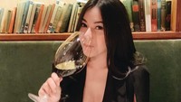 Enjoy with my glass, kata Elvia dalam captions fotonya. Ia berpose santai sambil  menikmati segelas wine. Di depannya sudah ada piring yang jadi wadah makanannya.  Foto: instagram @elviacerolline