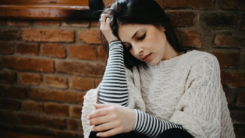 Unhappy housewife sitting near the window
