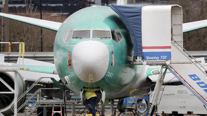 FILE - In this Dec. 16, 2019, file photo, a worker looks up underneath a Boeing 737 MAX jet, in Renton, Wash. Boeing has found a new software problem on its grounded 737 Max jetliner. The aircraft maker said, Friday, Jan. 17, 2020, it is making the necessary changes and working with the Federal Aviation Administration. (AP Photo/Elaine Thompson, File)