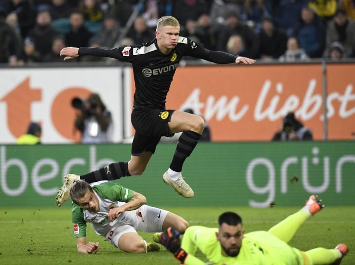 Dortmund's Norwegian forward Erling Braut Haaland jumps over Augsburg's Czech goalkeeper Tomas Koubek and Croatian defender Tin Jedvaj after he scored during the German first division Bundesliga football match Augsburg v Borussia Dortmund in Augsburg, on January 18, 2020. (Photo by THOMAS KIENZLE / AFP) / DFL REGULATIONS PROHIBIT ANY USE OF PHOTOGRAPHS AS IMAGE SEQUENCES AND/OR QUASI-VIDEO