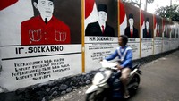 Seorang warga melintas di samping dinding jalan yang dihiasi mural wajah-wajah Presiden Indonesia di Kota Bogor, Jawa Barat, Minggu (19/1/2020).