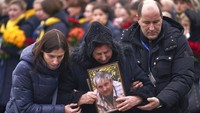 Keluarga salah satu korban tewas dalam insiden pesawat jatuh di Iran menangis saat menyambut kedatangan 11 jenazah di Kiev, Ukraina, pada Minggu (19/1) waktu setempat. Ukrainian Presidential Press Office via AP.