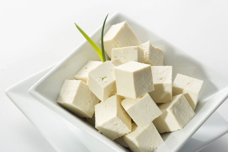 Tofu cubes in a white bowl garnished with spring onion.
